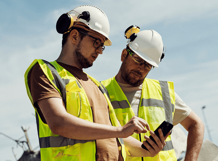 Two construction workers looking at a phone